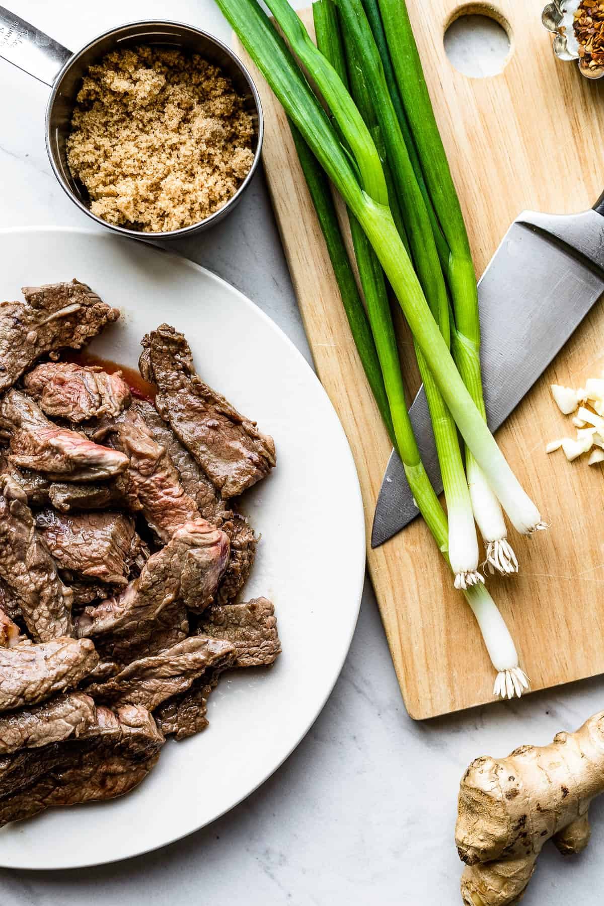 Green Onions, Garlic, Soy Sauce, Slices of Flank Steak and the Rest of the Ingredients on Two Different Baking Sheets