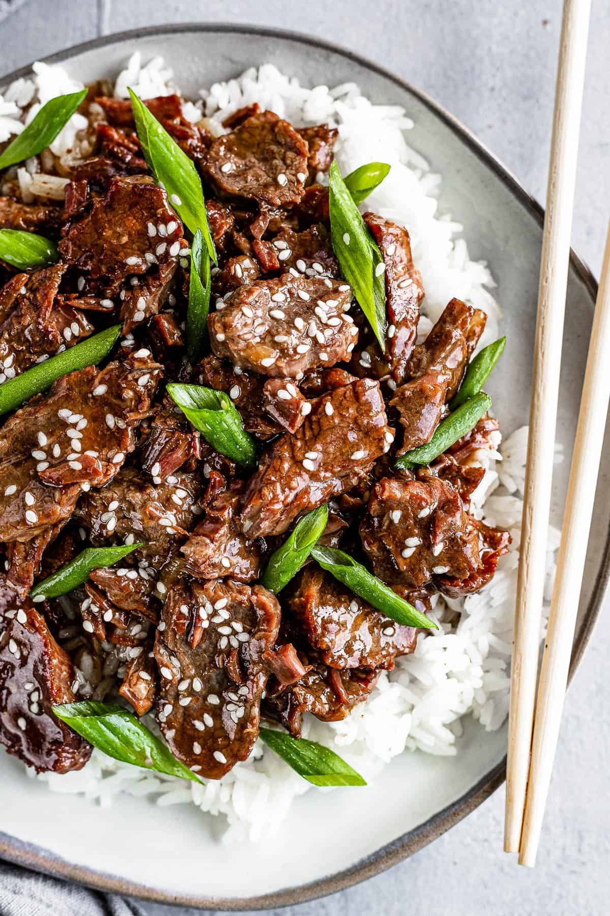 Instant Pot Mongolian Beef Over White Rice on a Gray Plate with a Pair of Wooden Chopsticks