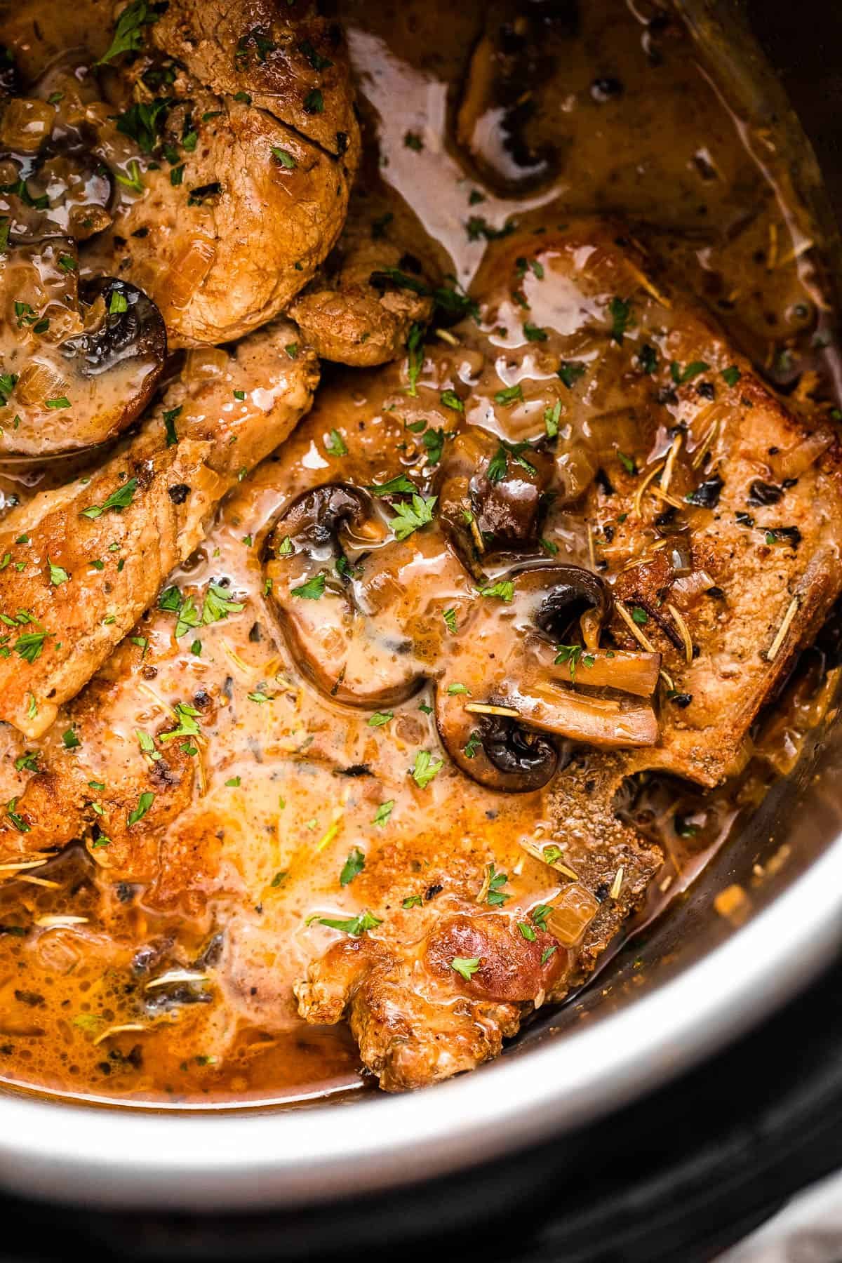 close up shot of pork chops in the instant pot topped with mushroom gravy sauce