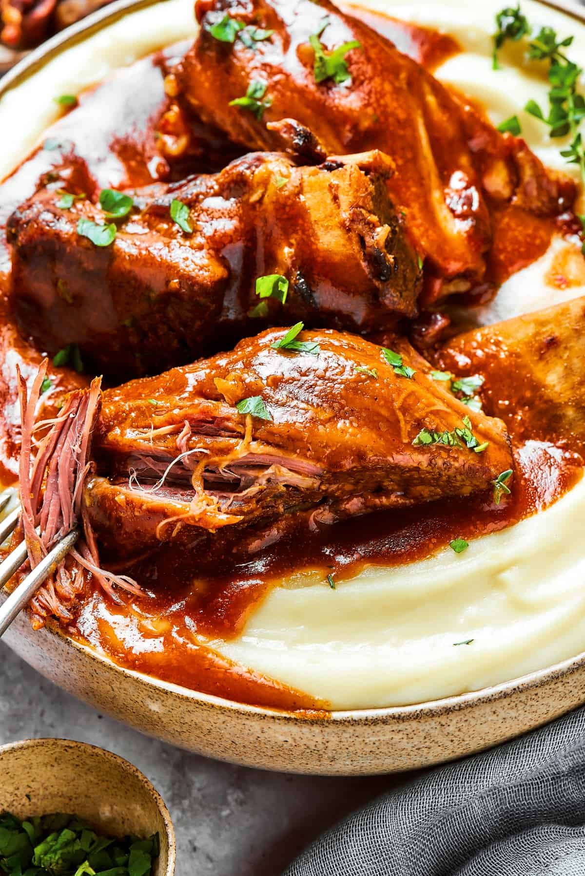 A fork pulling the meat of the short ribs apart, to show its tenderness.