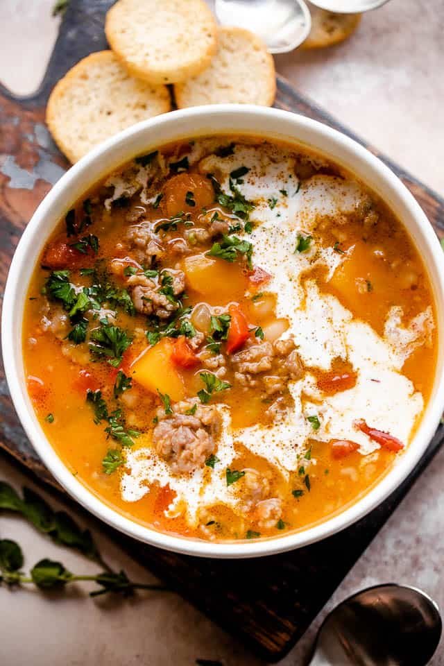 Overhead shot of butternut squash and sausage soup served in a white bowl.