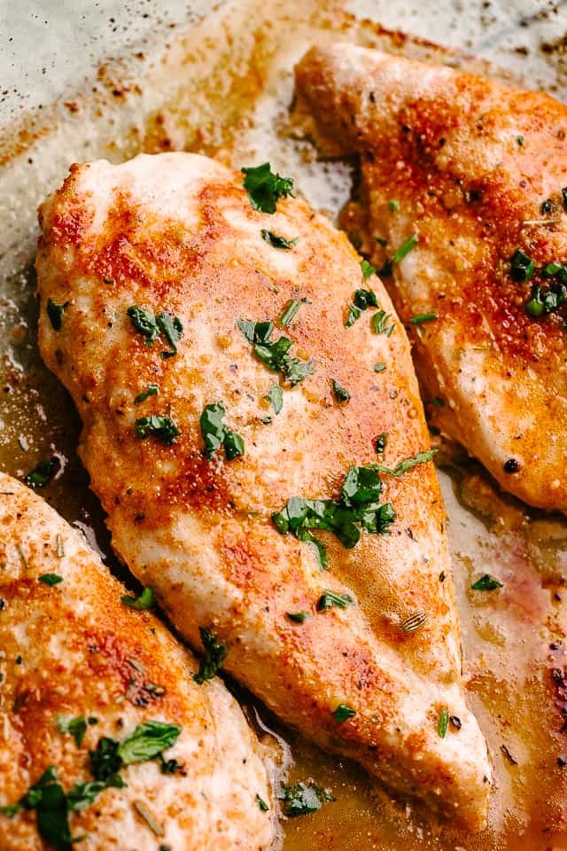 Photo of oven baked chicken breasts garnished with parsley.