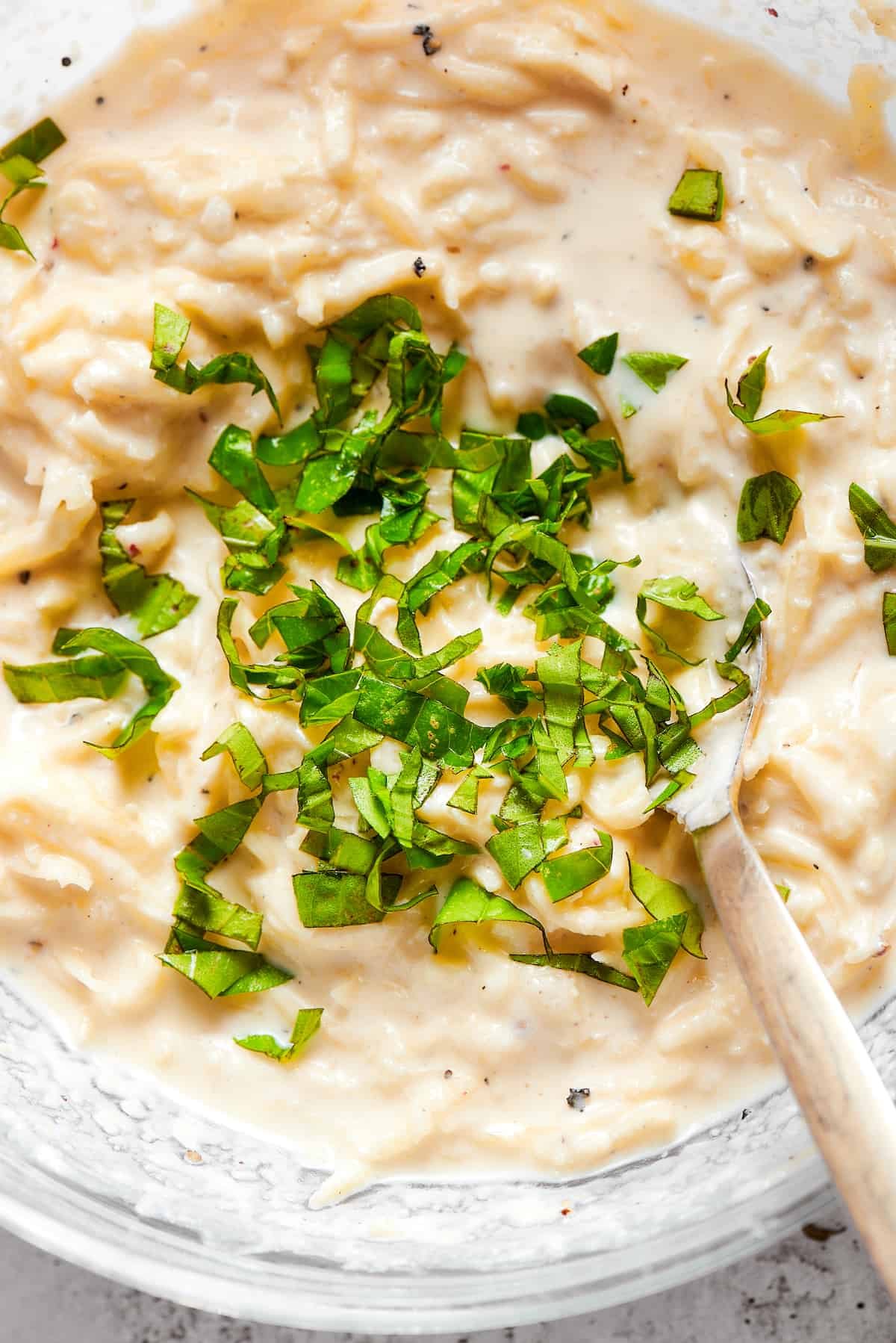 Close up overhead view of basil being mixed into a cheese filling.