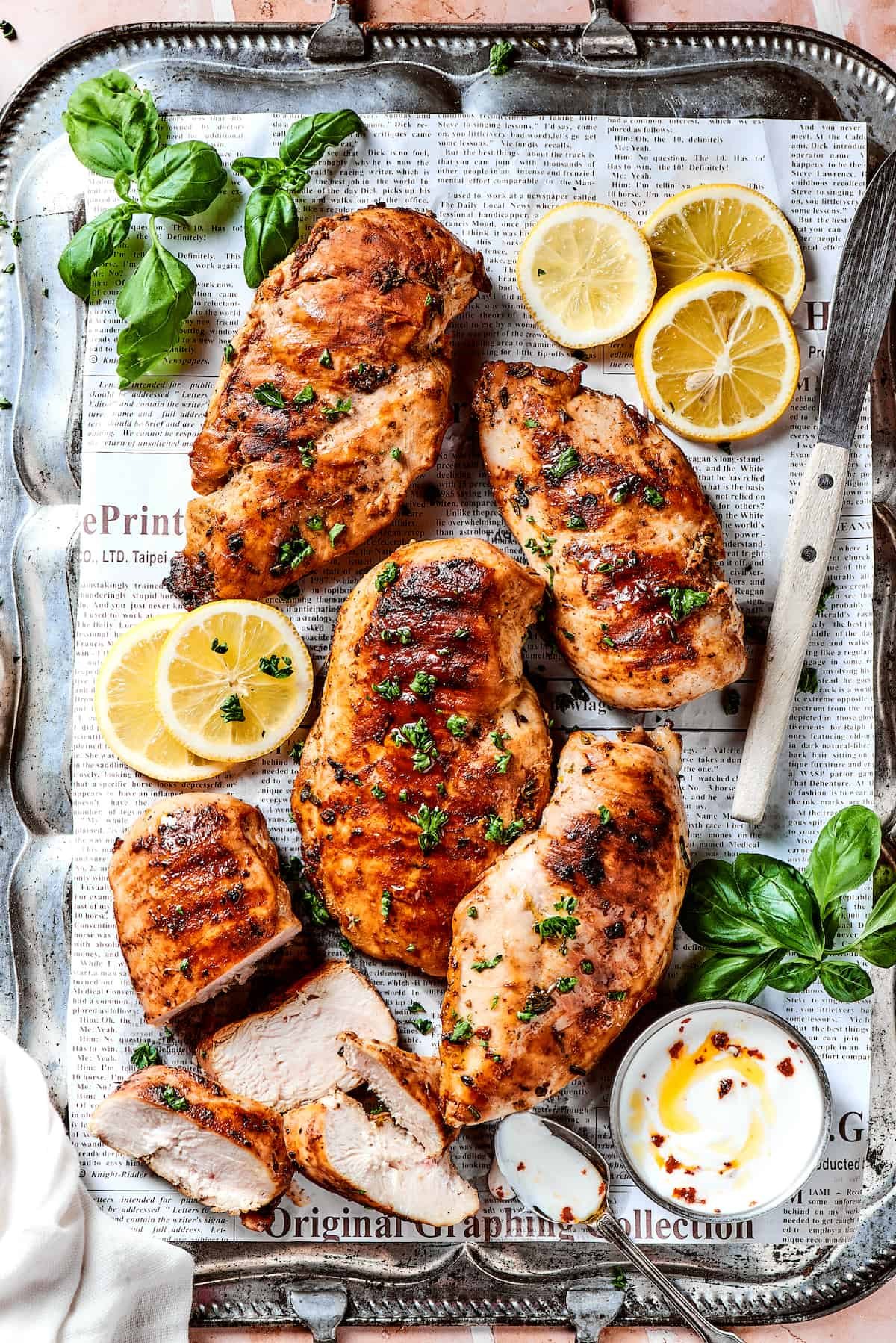 A large platter of grilled lemon chicken breasts.