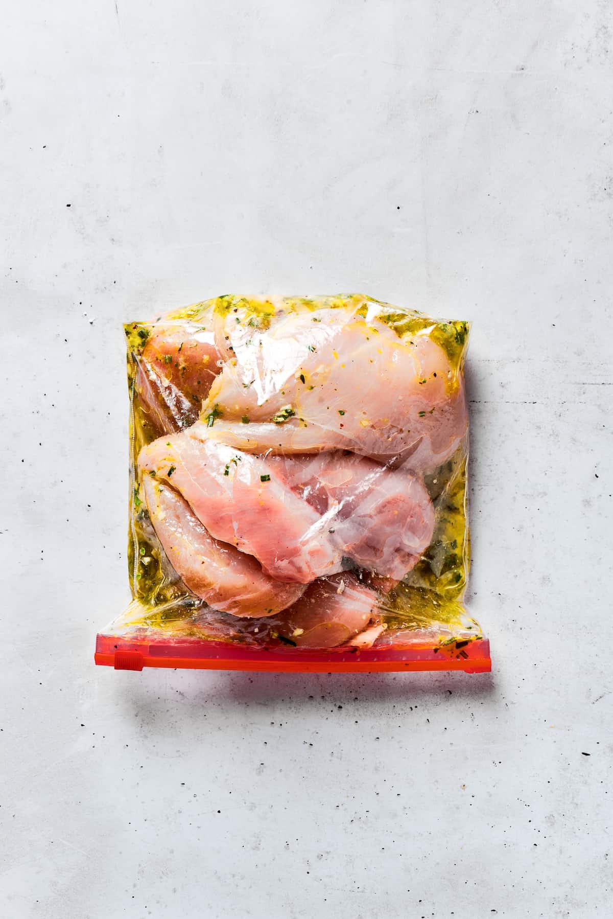 Chicken breasts in a zip-top bag coated with marinade.