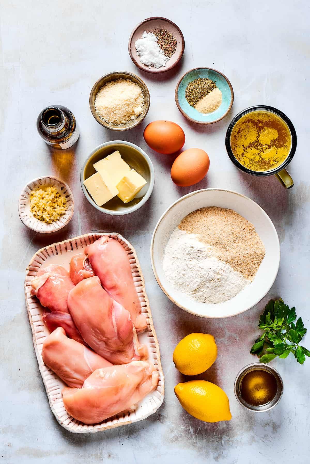 From top: salt, pepper, garlic, Italian seasoning, broth, eggs, breadcrumbs, flour, parsley, olive oil, lemons, chicken breast, butter, garlic, parmesan, white wine.