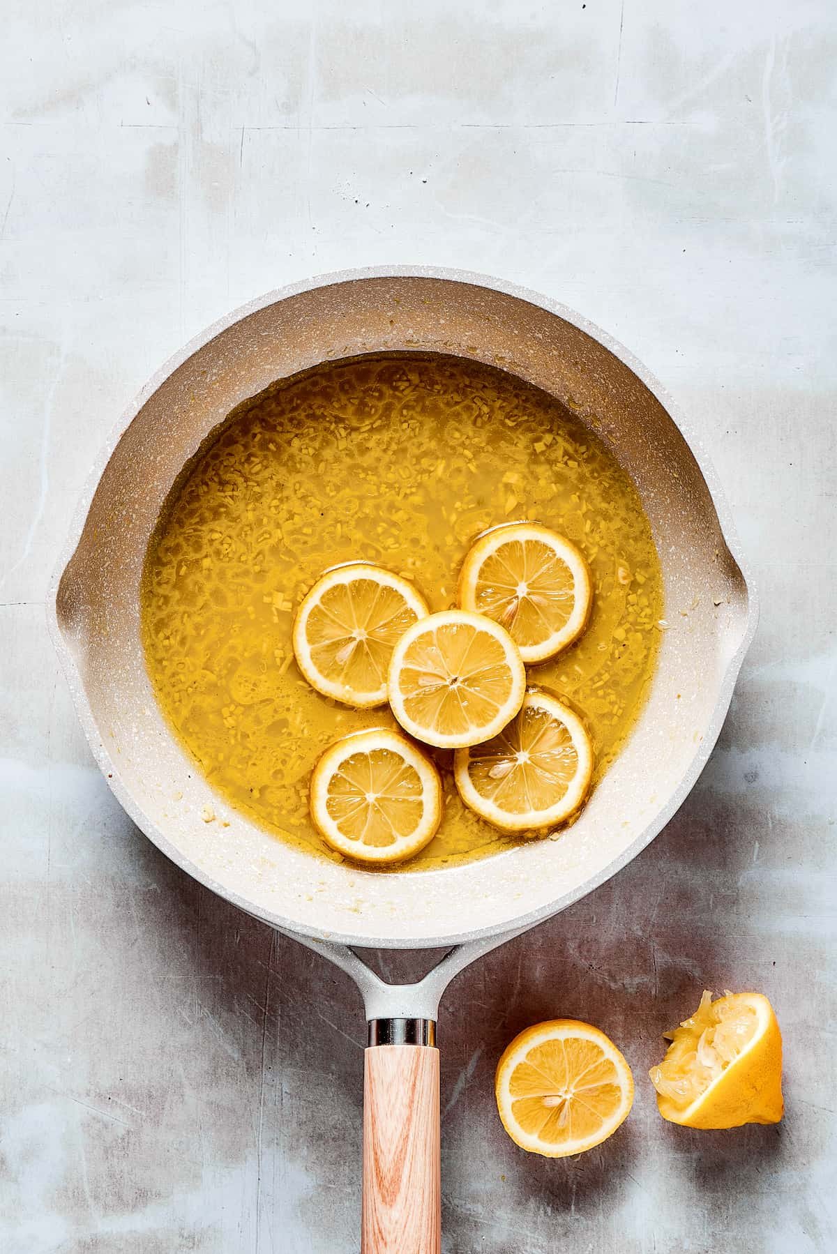 Lemon slices added to a skillet of sauce.