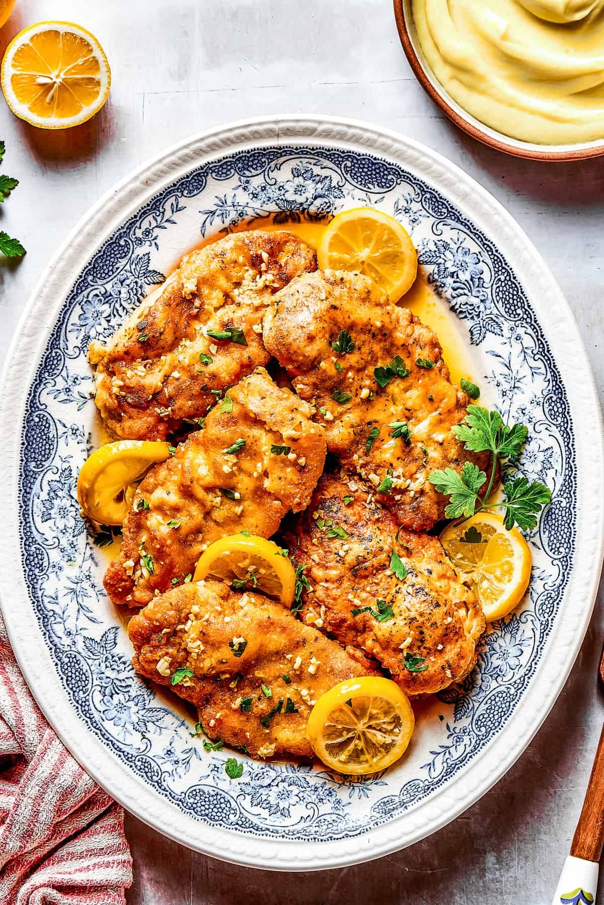 Lemon chicken breasts arranged on a blue oval plate.