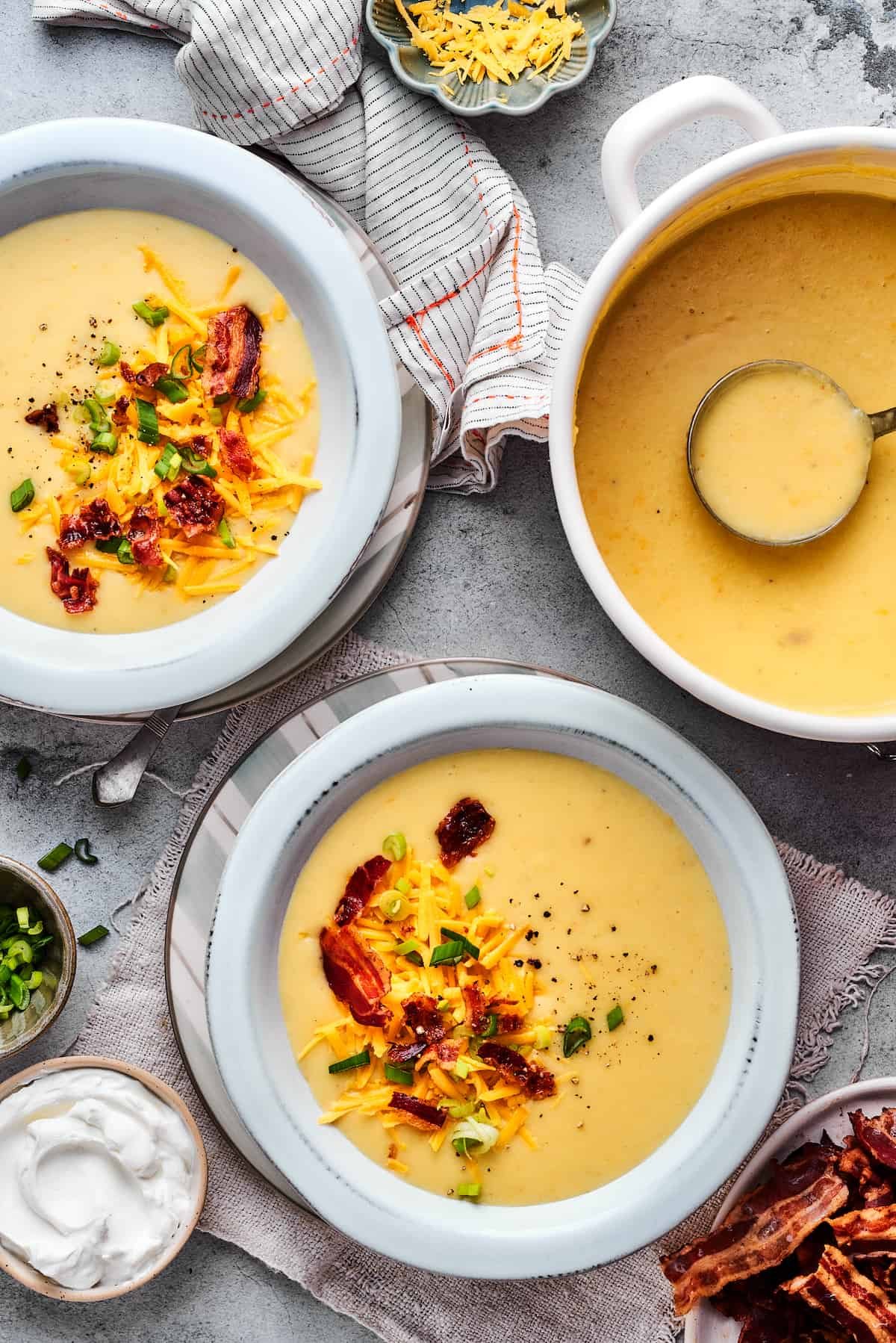 A pot of soup next to two bowls of soup.