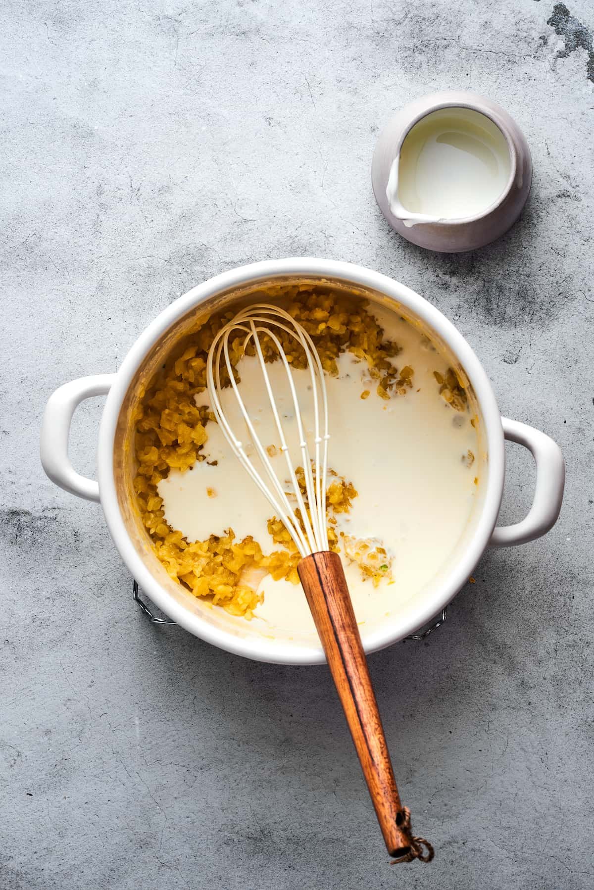 Whisking milk into a soup pot.