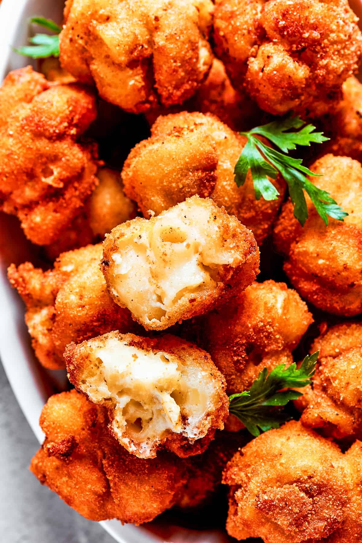 Overhead view of a serving bowl full of mac and cheese bites garnished with fresh herbs.