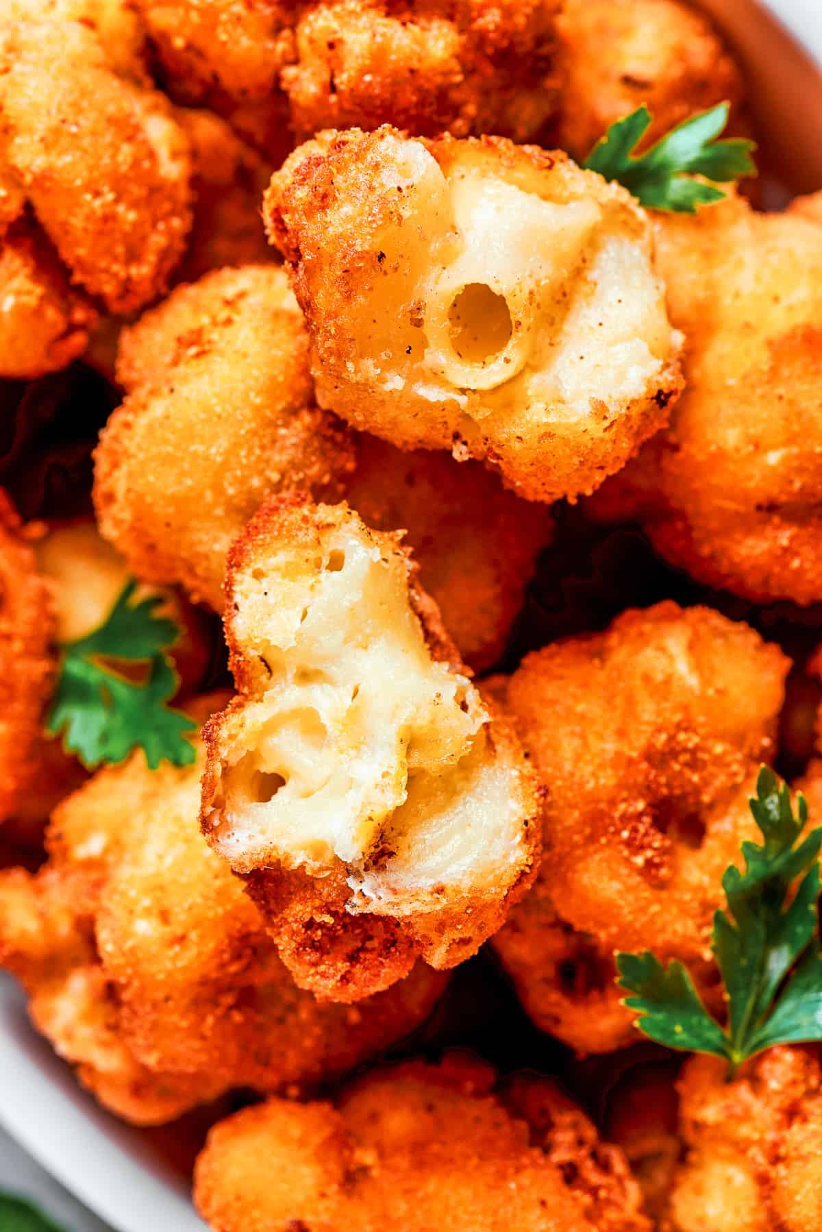 Close-up image of fried mac and cheese bites cut in half to showcase its texture inside.