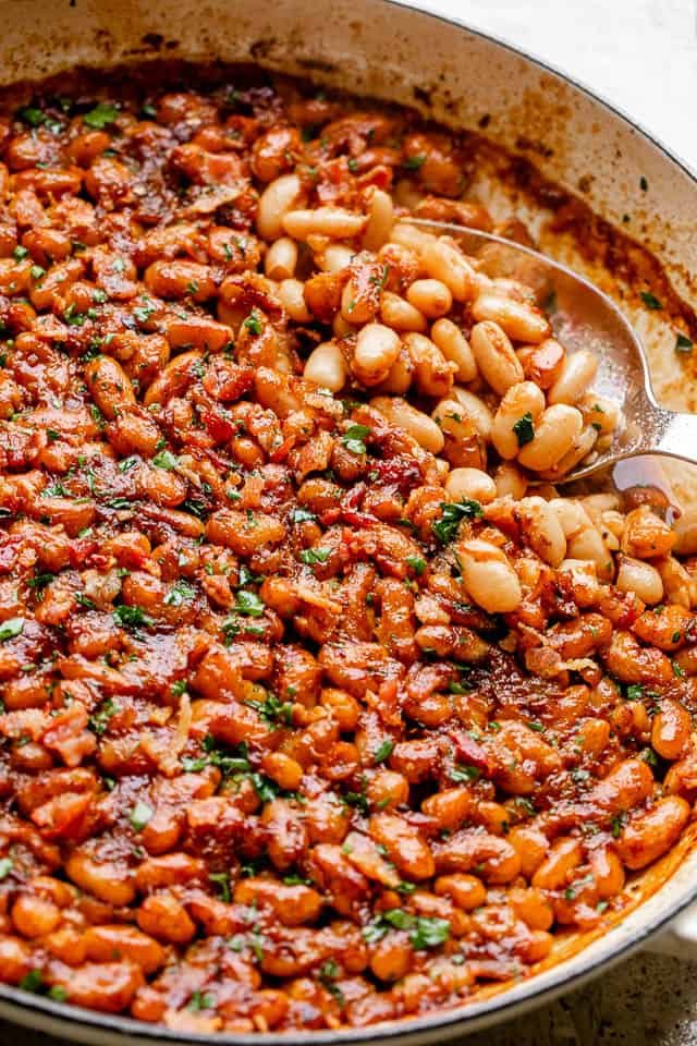 scooping out baked beans from a pot