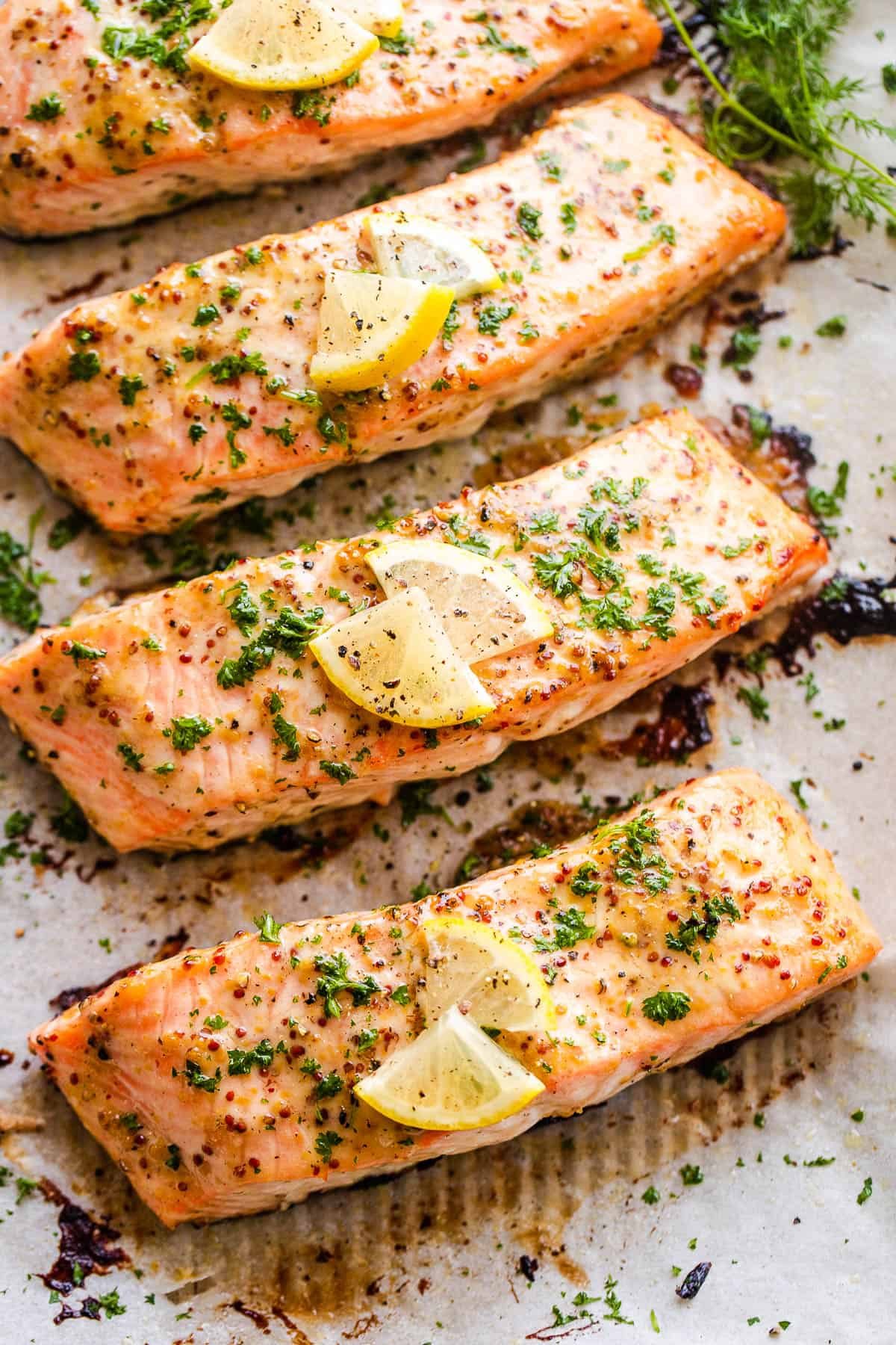four maple mustard salmon fillets arranged on a baking sheet