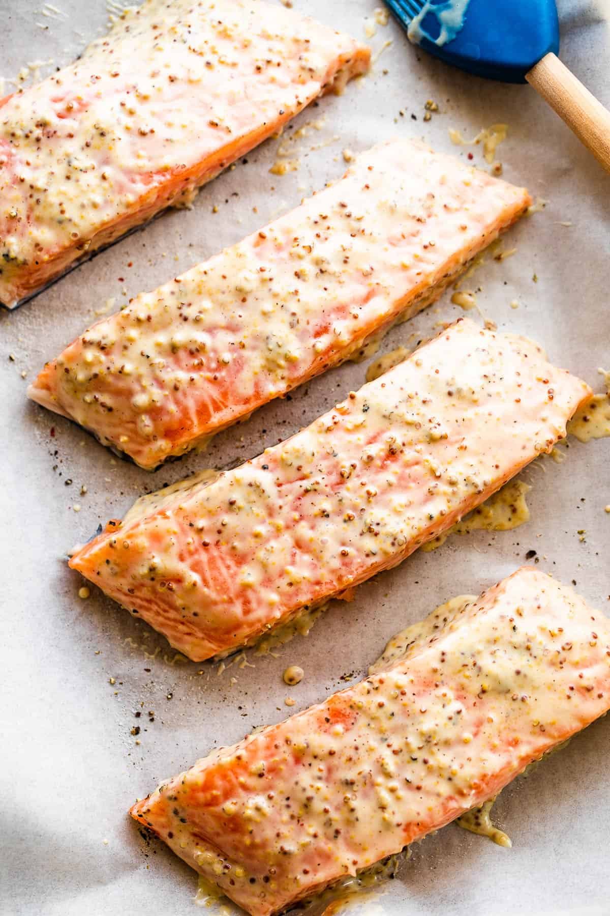 four raw salmon fillets arranged on a baking sheet