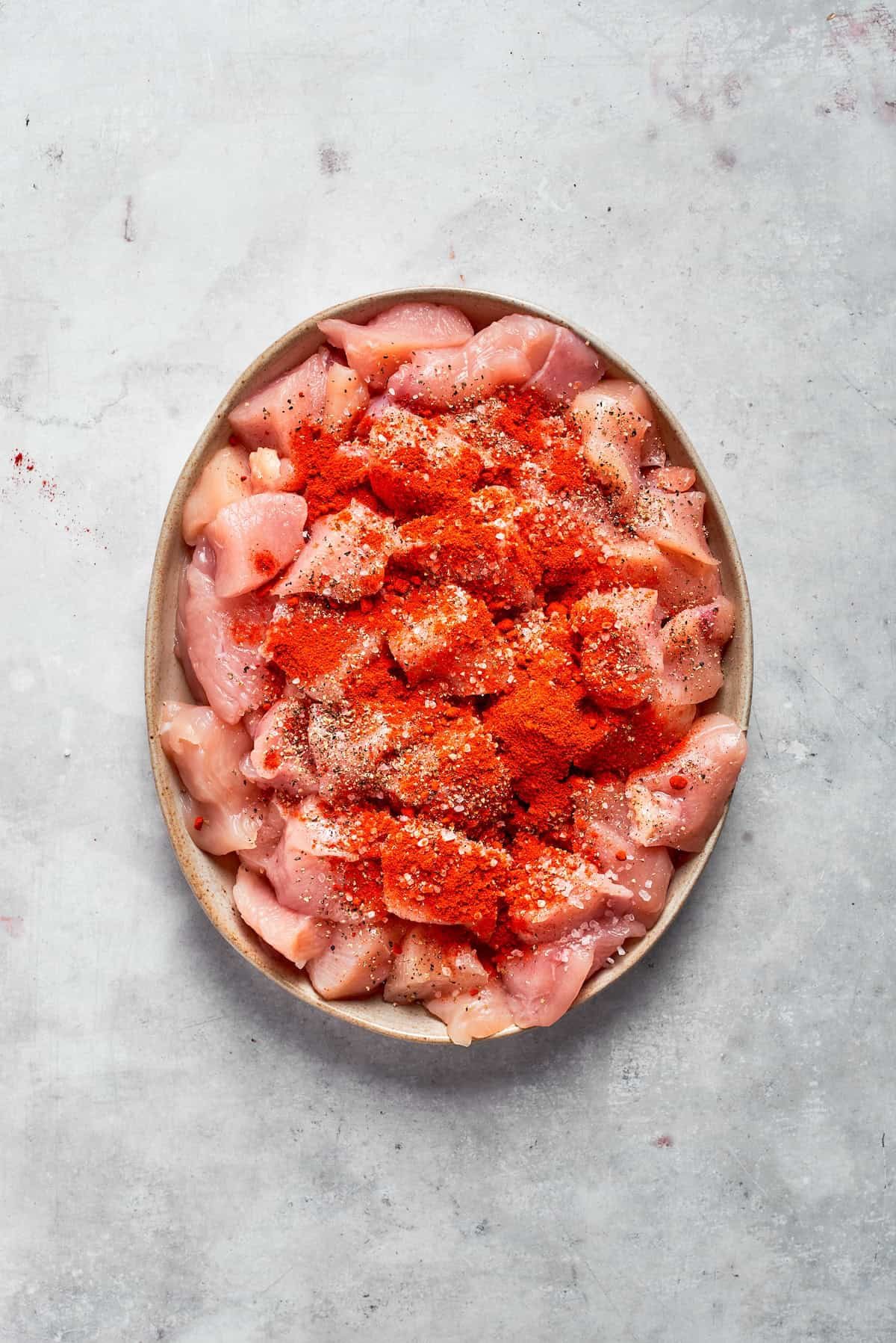 Chicken pieces with seasonings on a plate.