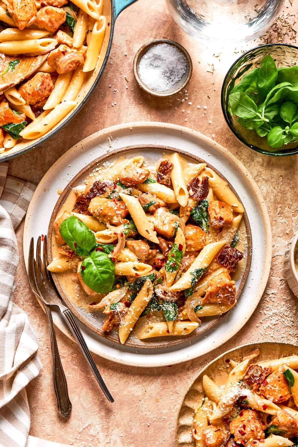 A plate of marry me chicken pasta garnished with fresh basil.