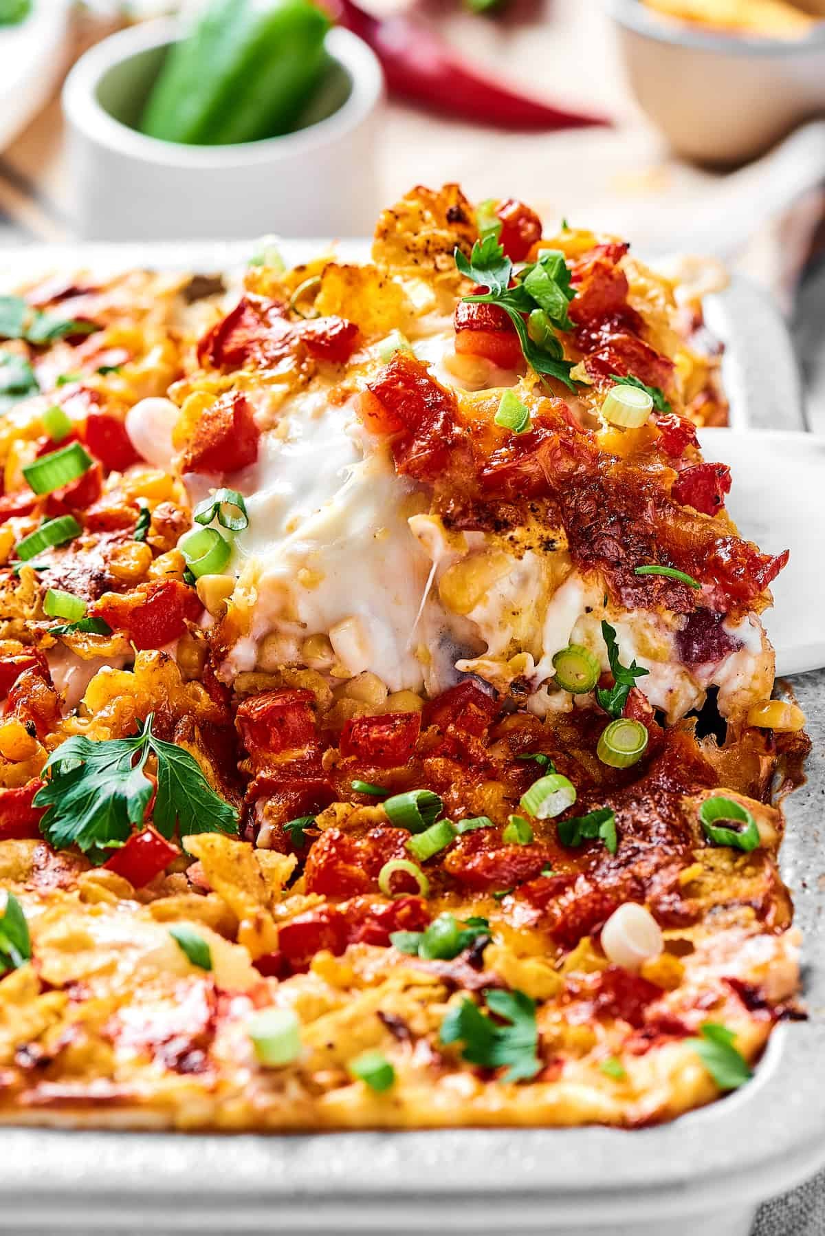 Close-up shot of a portion of casserole being lifted out of a baking dish.