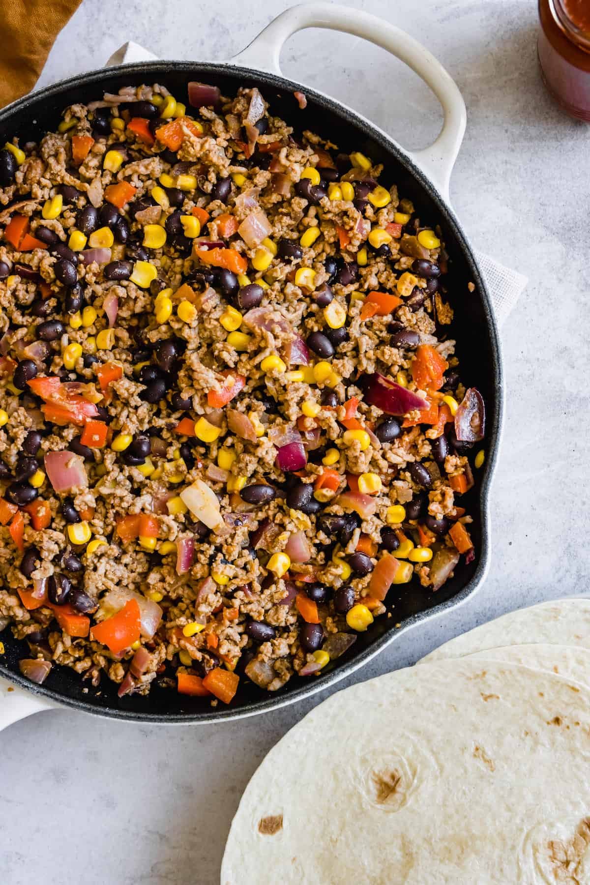 A Pan Filled with Mexican Lasagna Filling Beside Three Soft Tortillas