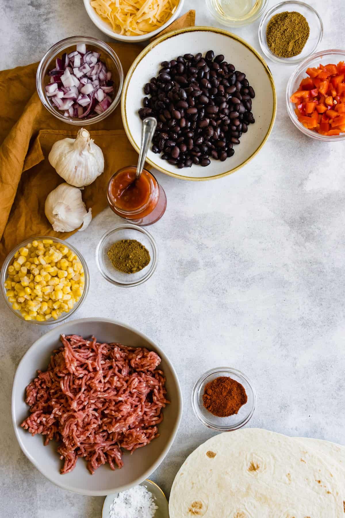 Black Beans, Corn, Diced Onions, Chili Powder and the Remaining Casserole Ingredients on a Countertop