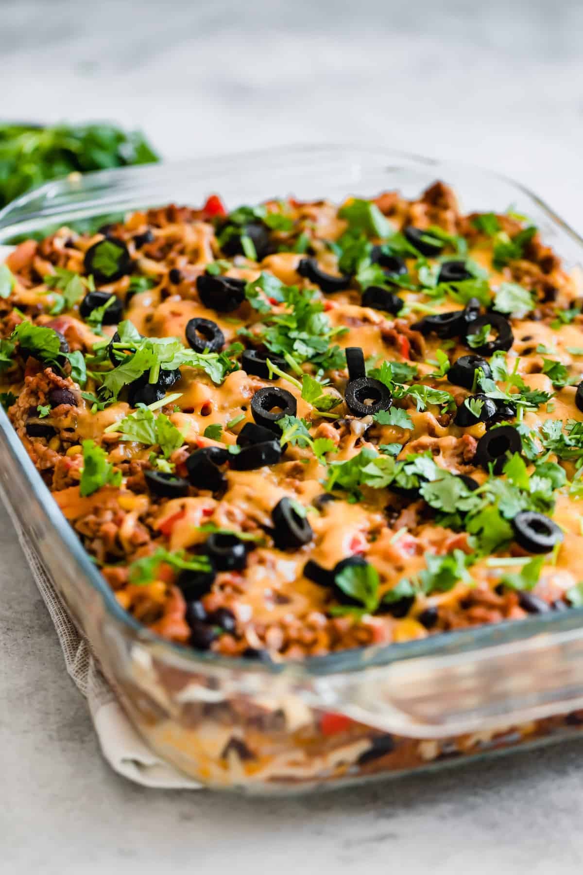 A Taco Casserole in a Glass Pan on Top of a White and Tan Dish Towel