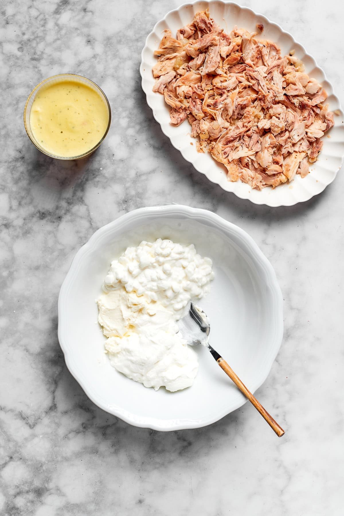A bowl of flour and a plate of chicken.