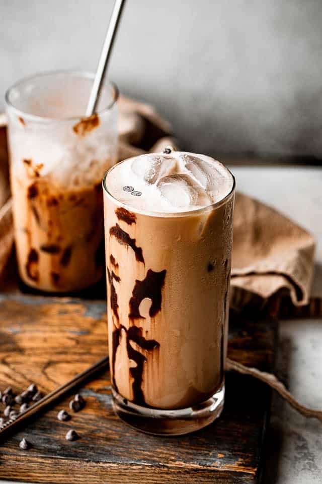 top side view of two drinking glasses filled with iced coffee and set on top of brown board
