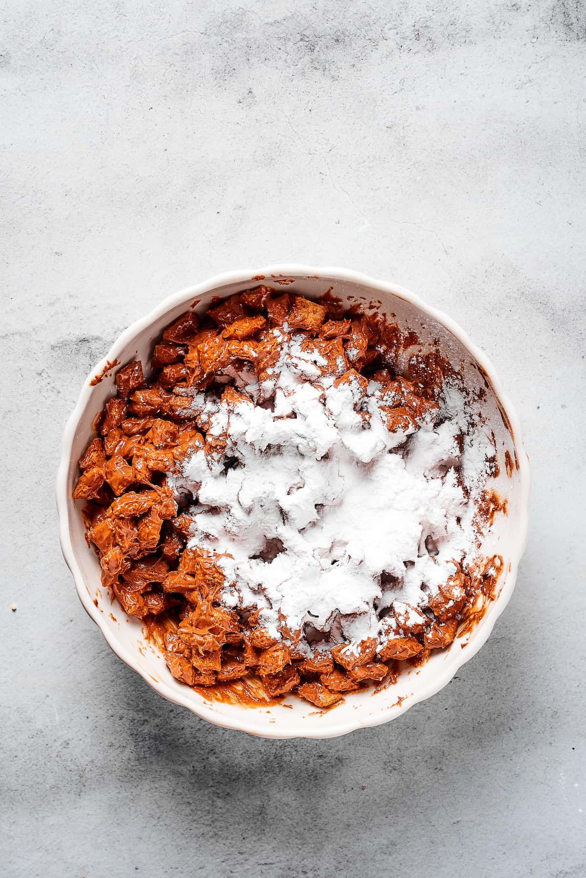 Powdered sugar dumped in a bowl of coated cereal.
