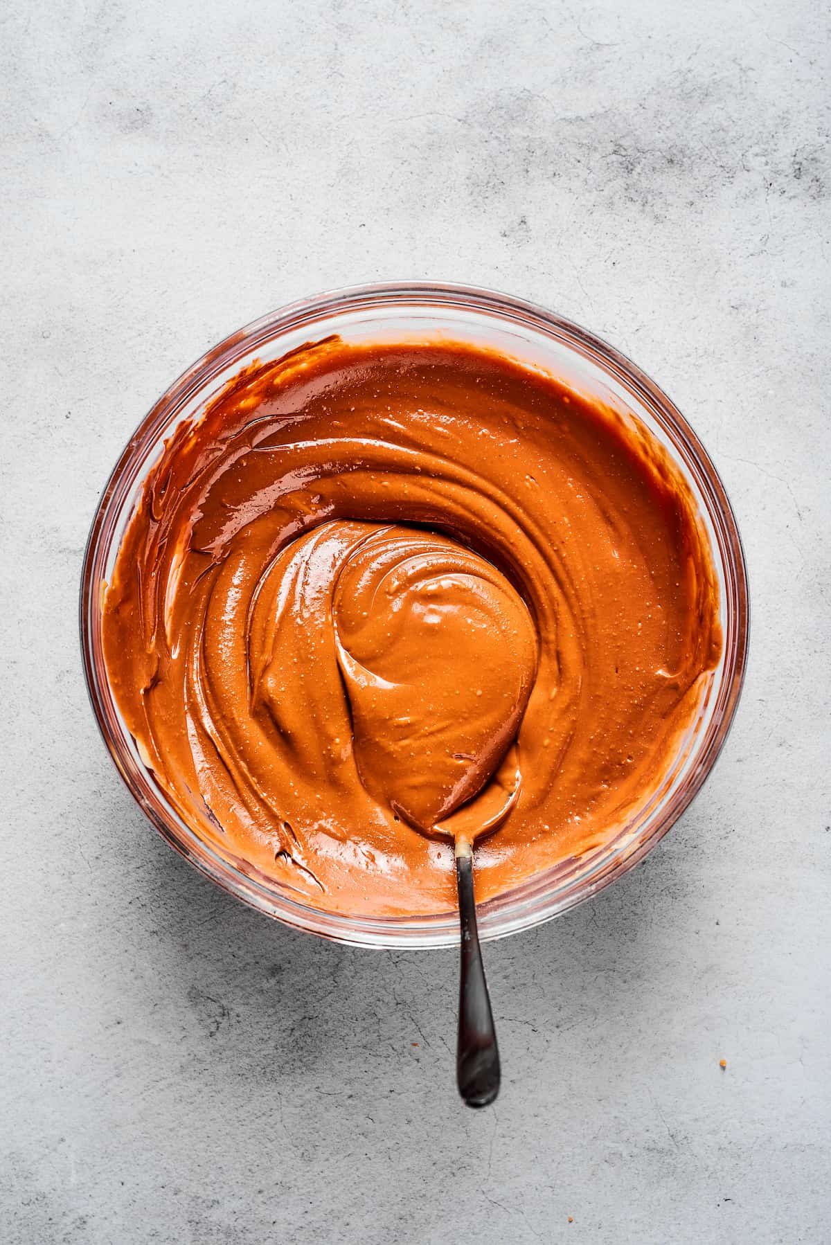 A smooth blend of melted peanut butter, chocolate, butter, vanilla, and sea salt in a glass mixing bowl.