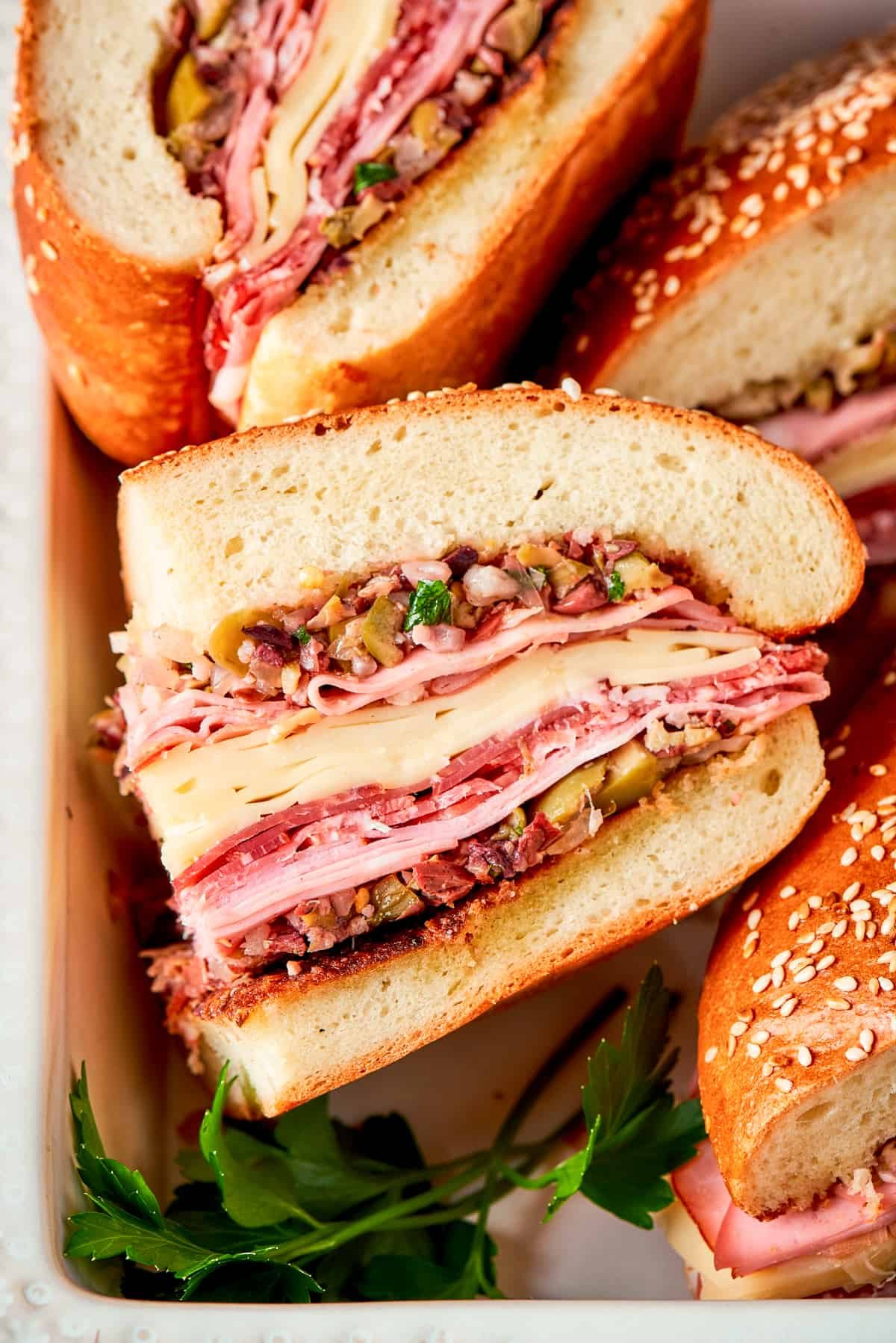 Muffaletta sandwich are shown on their sides with meat and cheese visible.