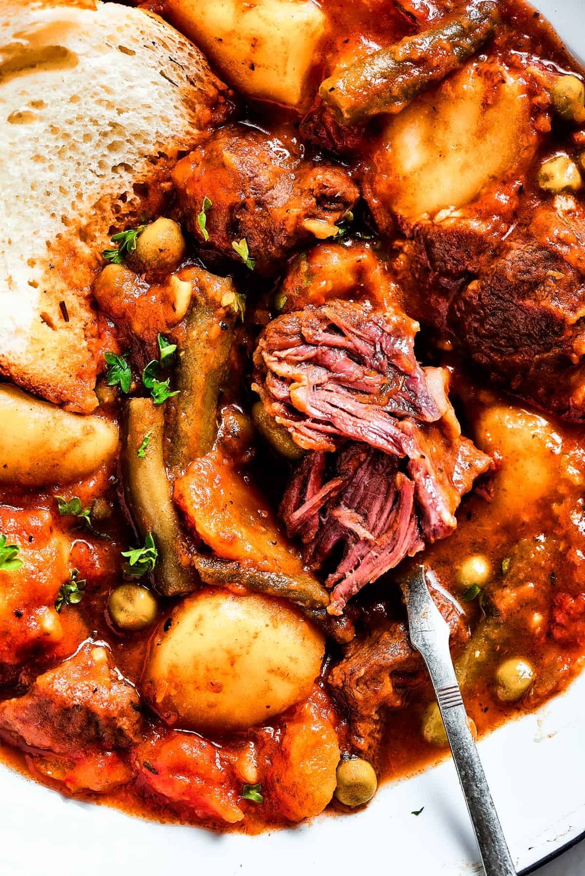 Close-up shot of a piece of white bread dipped in Mulligan stew.
