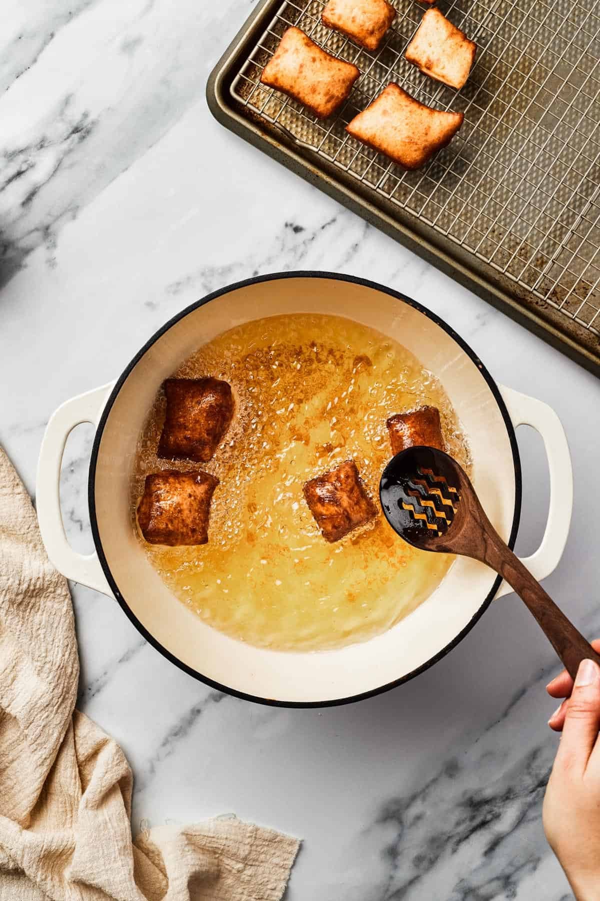 Browned, fried squares of dough in a Dutch oven partially filled with hot oil.