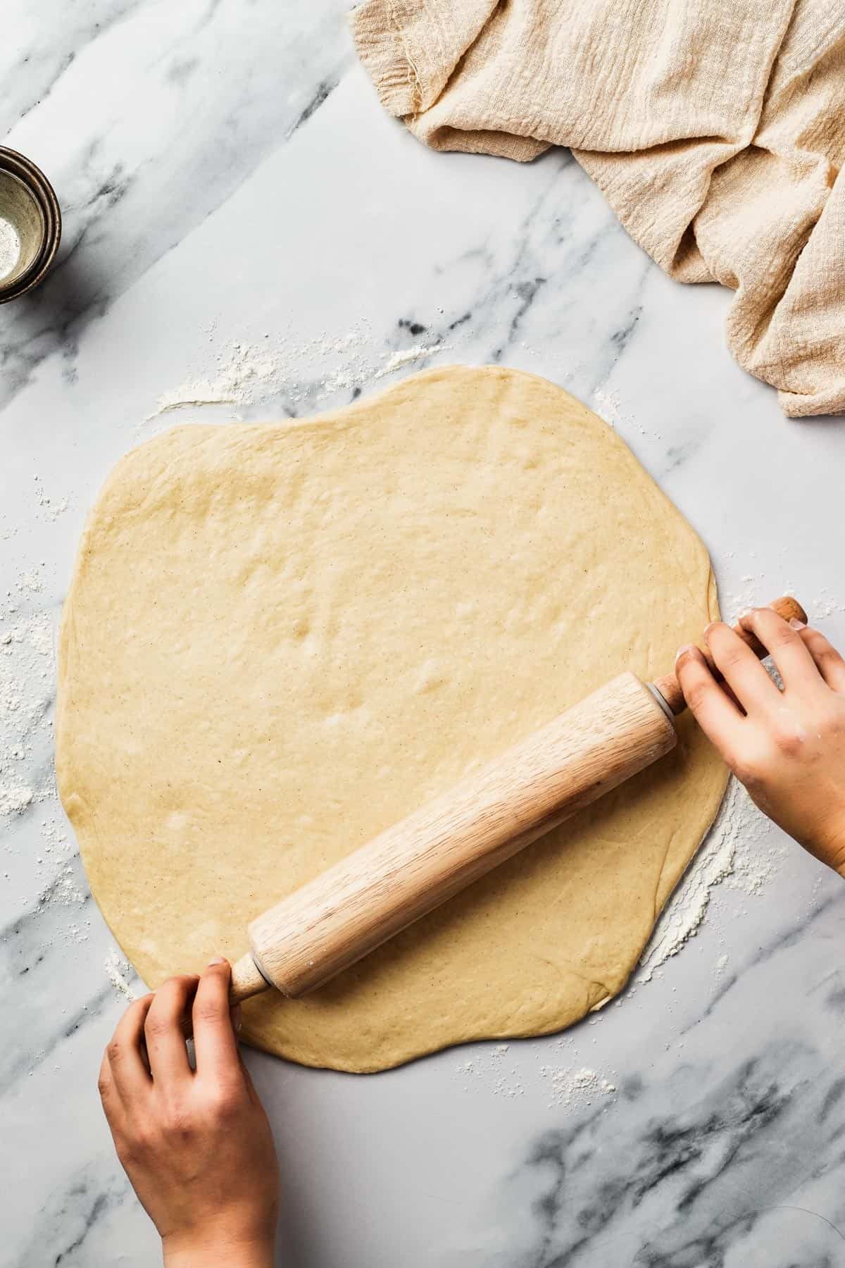 Dough being rolled out on a marble work surface.