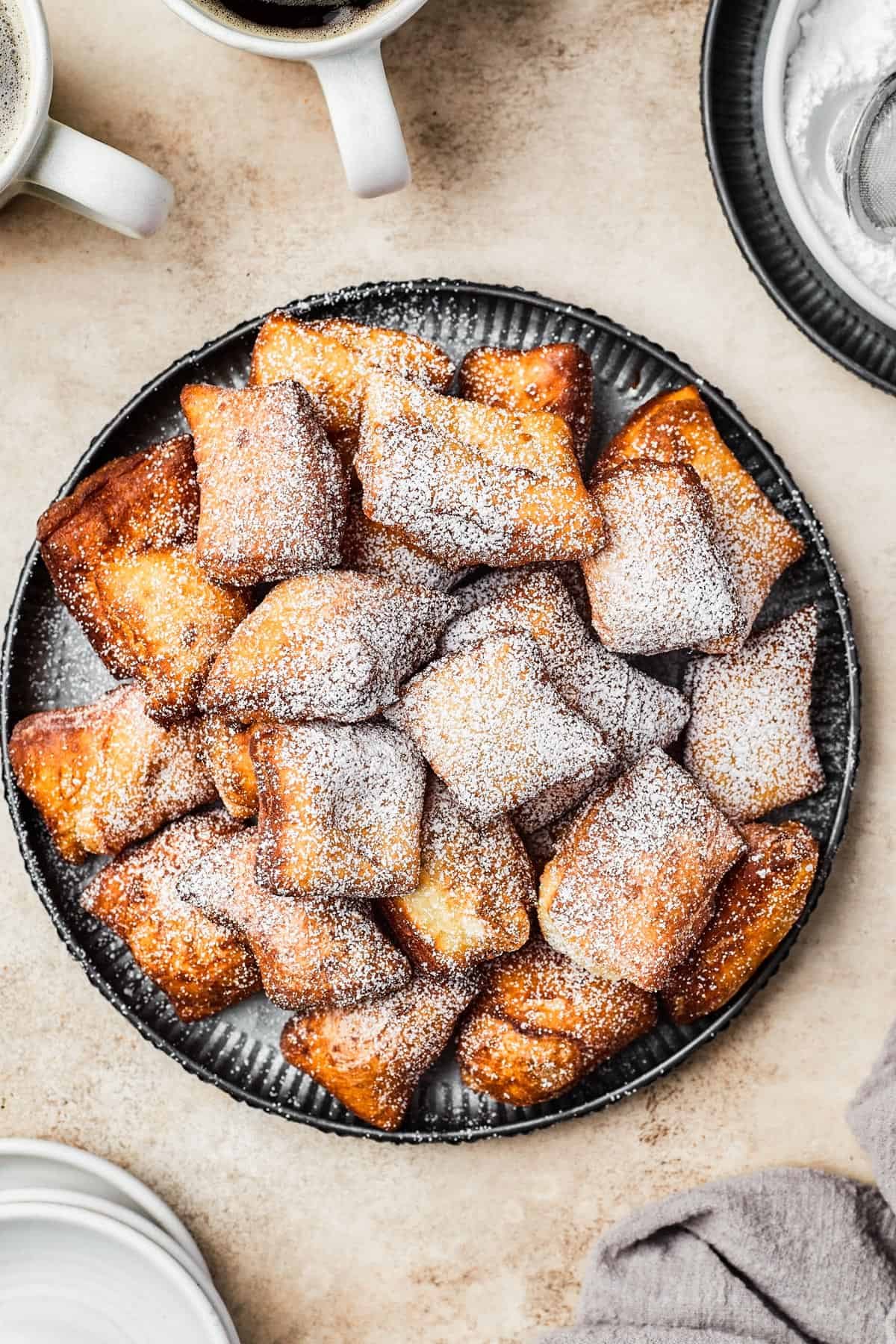 A plate of fried beignets, dusted with powdered sugar.