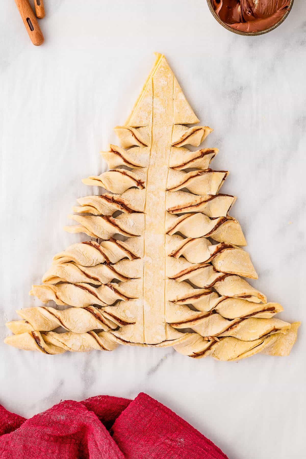 The unbaked puff pastry tree, with the horizontal strips twisted to show the filling.