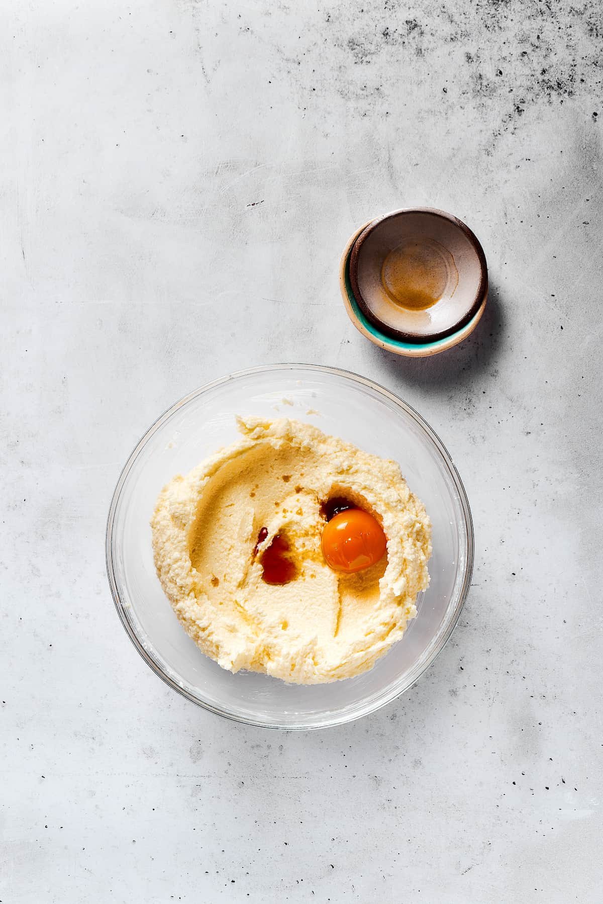 Adding egg yolks, vanilla, and other ingredients to creamed butter and sugar.