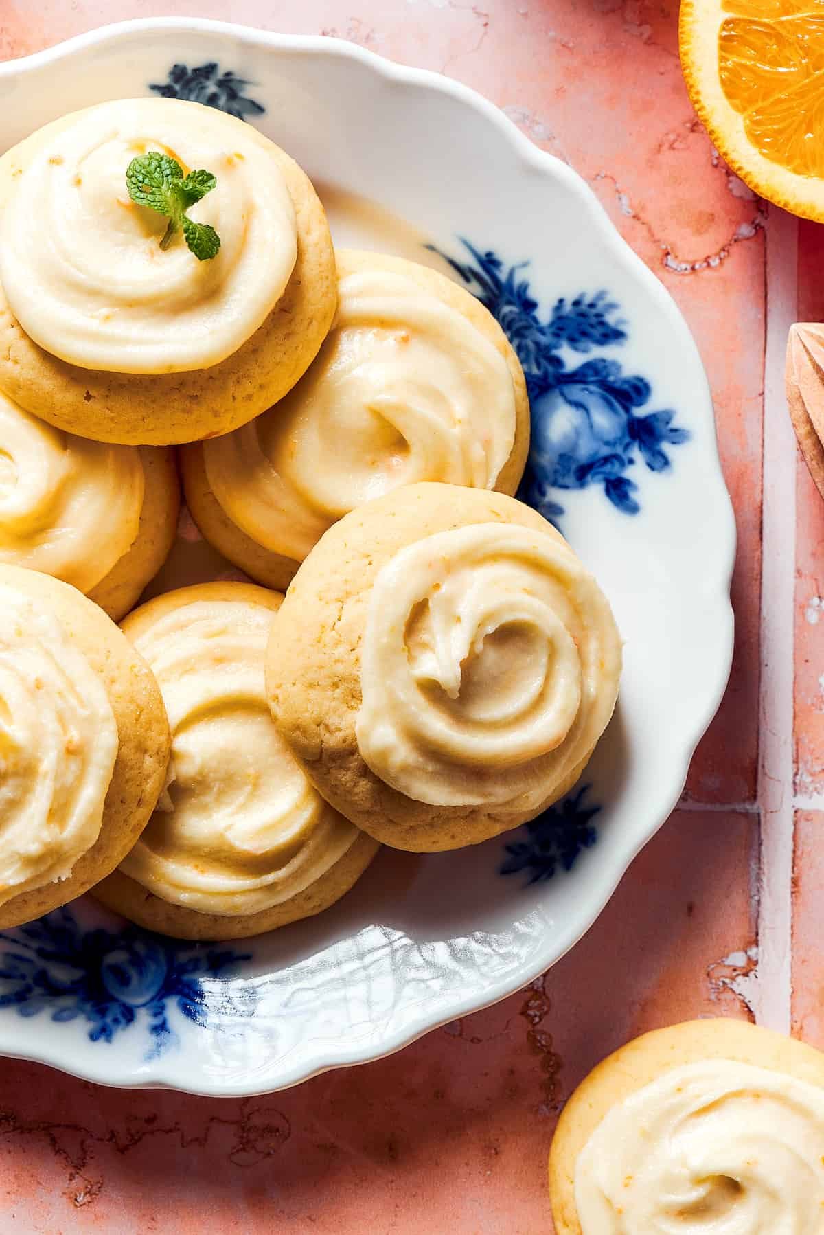 A blue and white flowered plate with iced orange cookies.