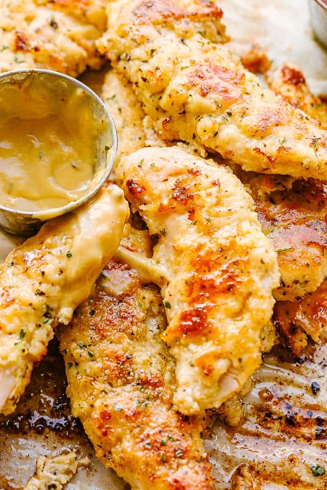 A close-up photo of chicken tenders and a small serving bowl filled with mustard sauce.
