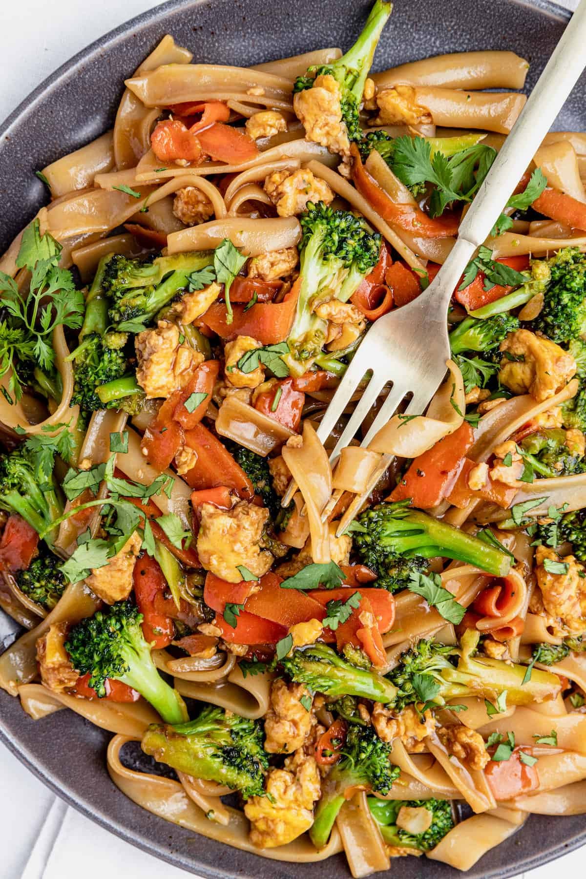 A Fork Digging Into a Big Plate of Pad See Ew