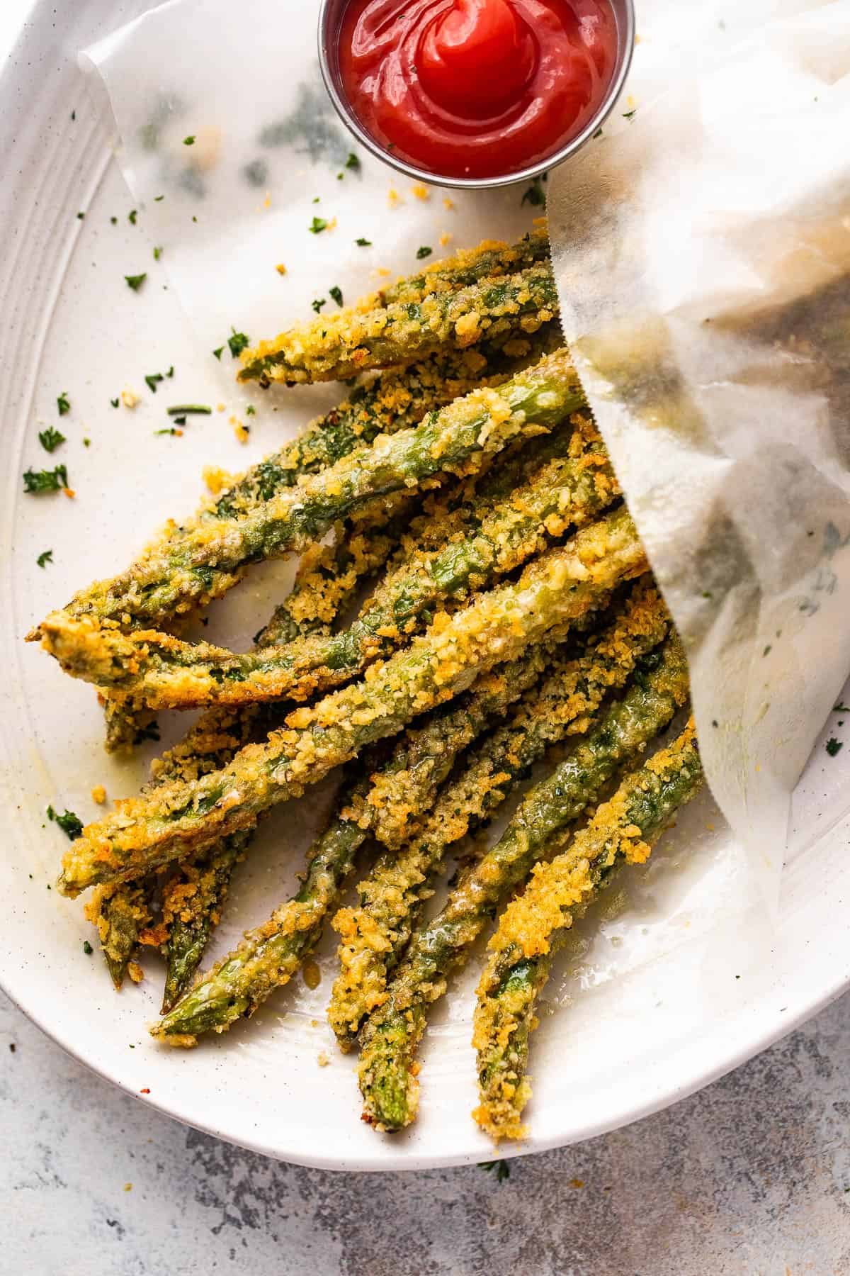 overhead shot of baked parmesan panko asparagus fries served with ketchup on the side