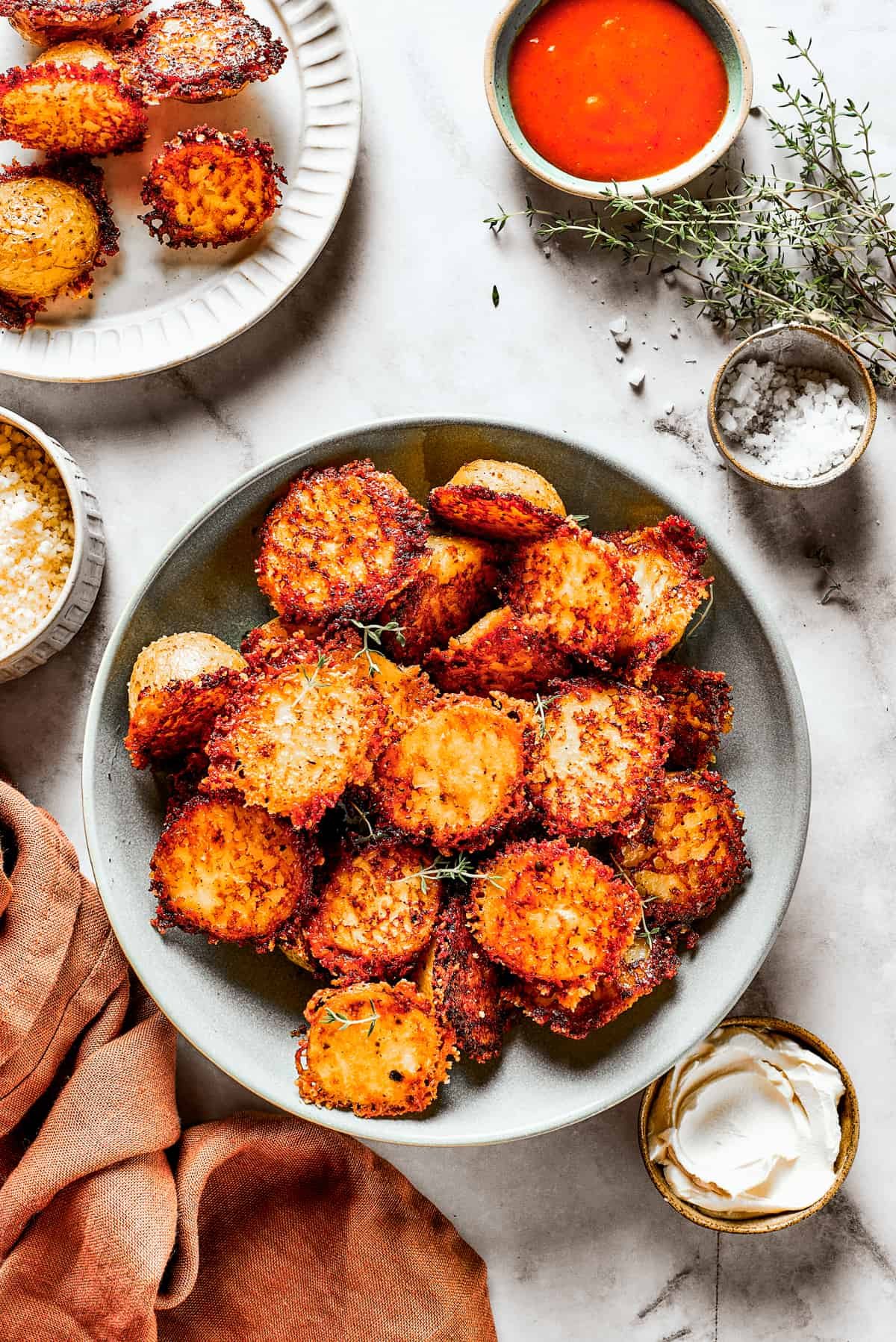 A bowl of baked potato halves crusted with parmesan cheese.