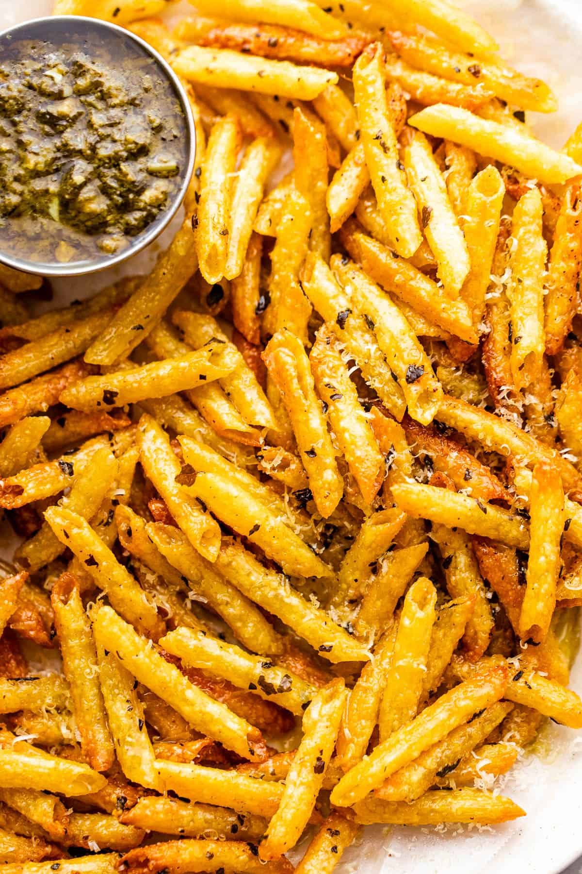 close up of baked pasta chips served with basil pesto