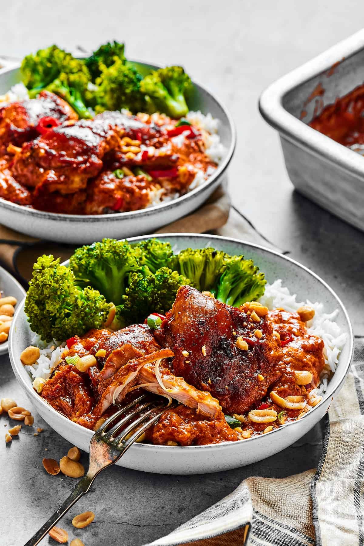 Two plates of saucy chicken and veggies.