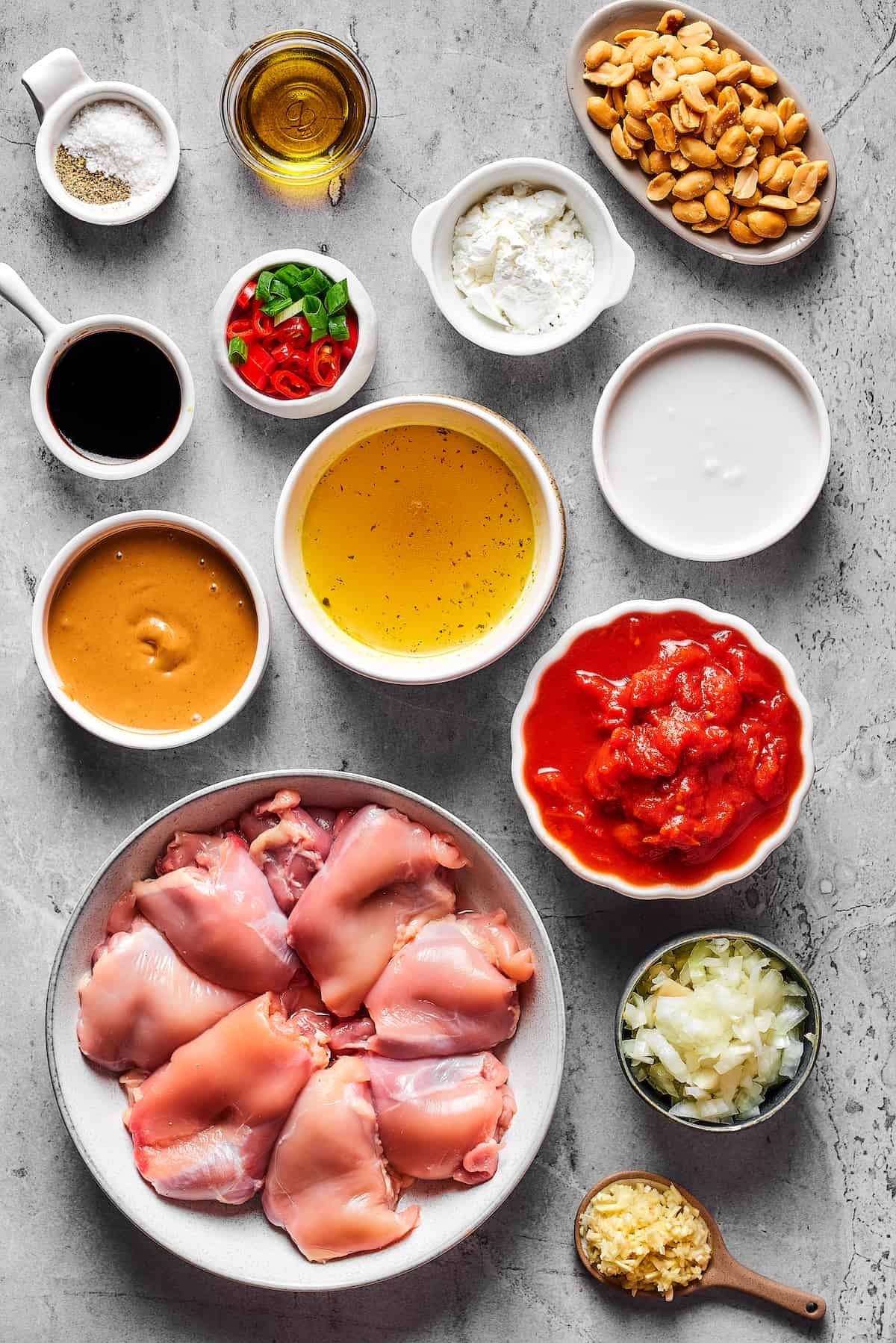 From top left: Salt, olive oil, roasted peanuts, soy sauce, sliced chilies and green onions, cornstarch, peanut butter, chicken stock, coconut milk, chicken thighs, crushed tomatoes, chopped onion, garlic.