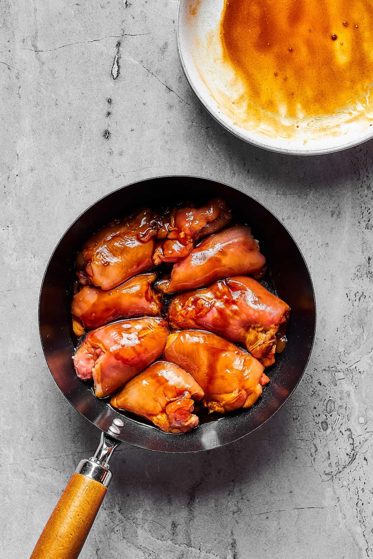 Chicken thighs cooking in a skillet.