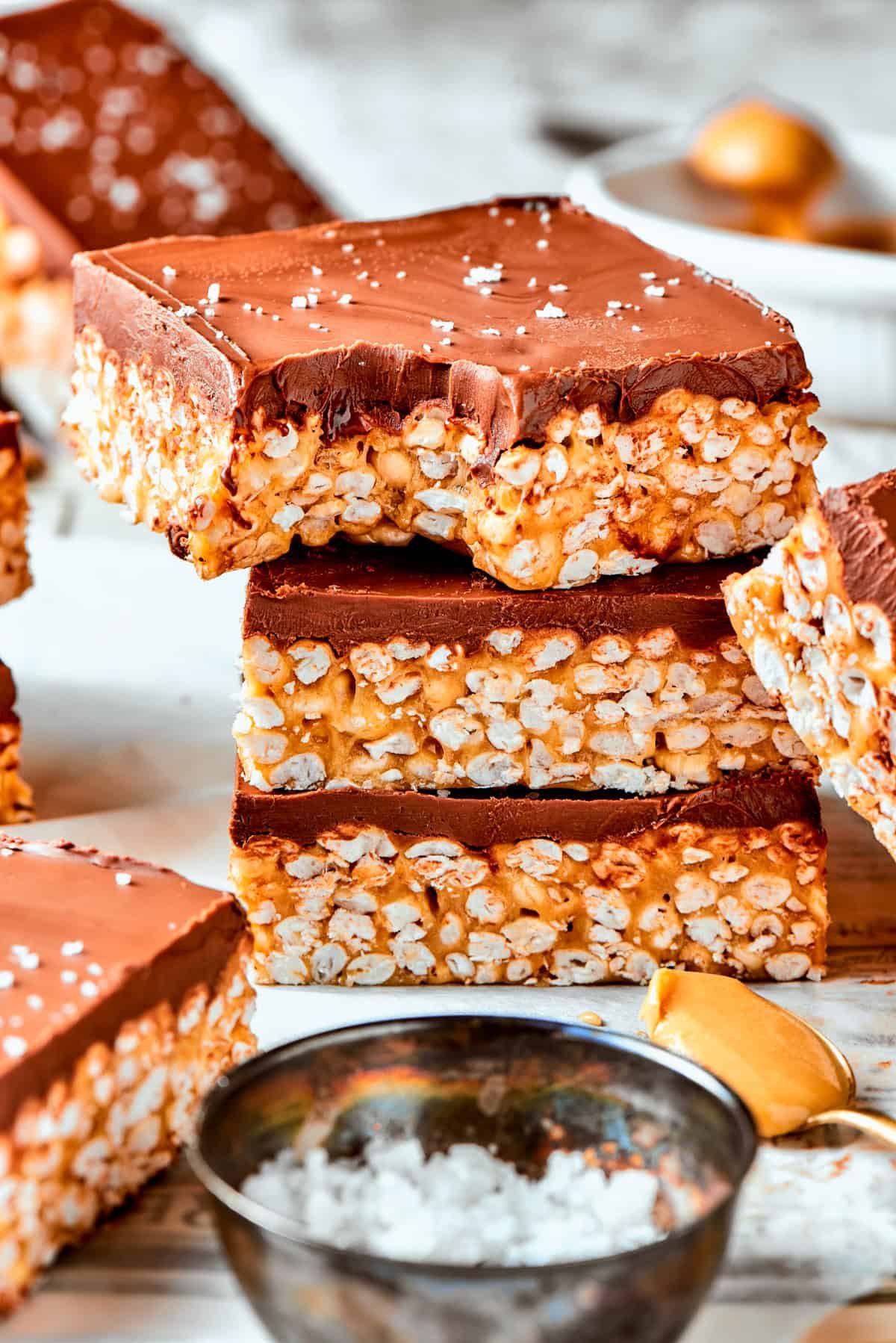 A stack of rice crispy treats and the top one has a bite taken out of it.