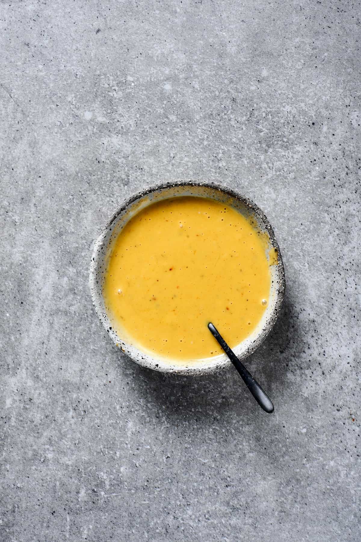 A small earthenware bowl of honey mustard sauce.