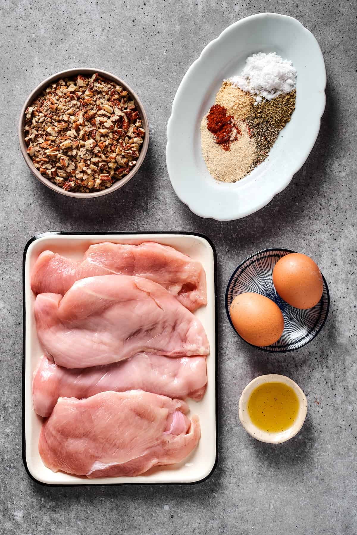 From top left: Chopped pecans, spices, chicken breast, eggs, olive oil.