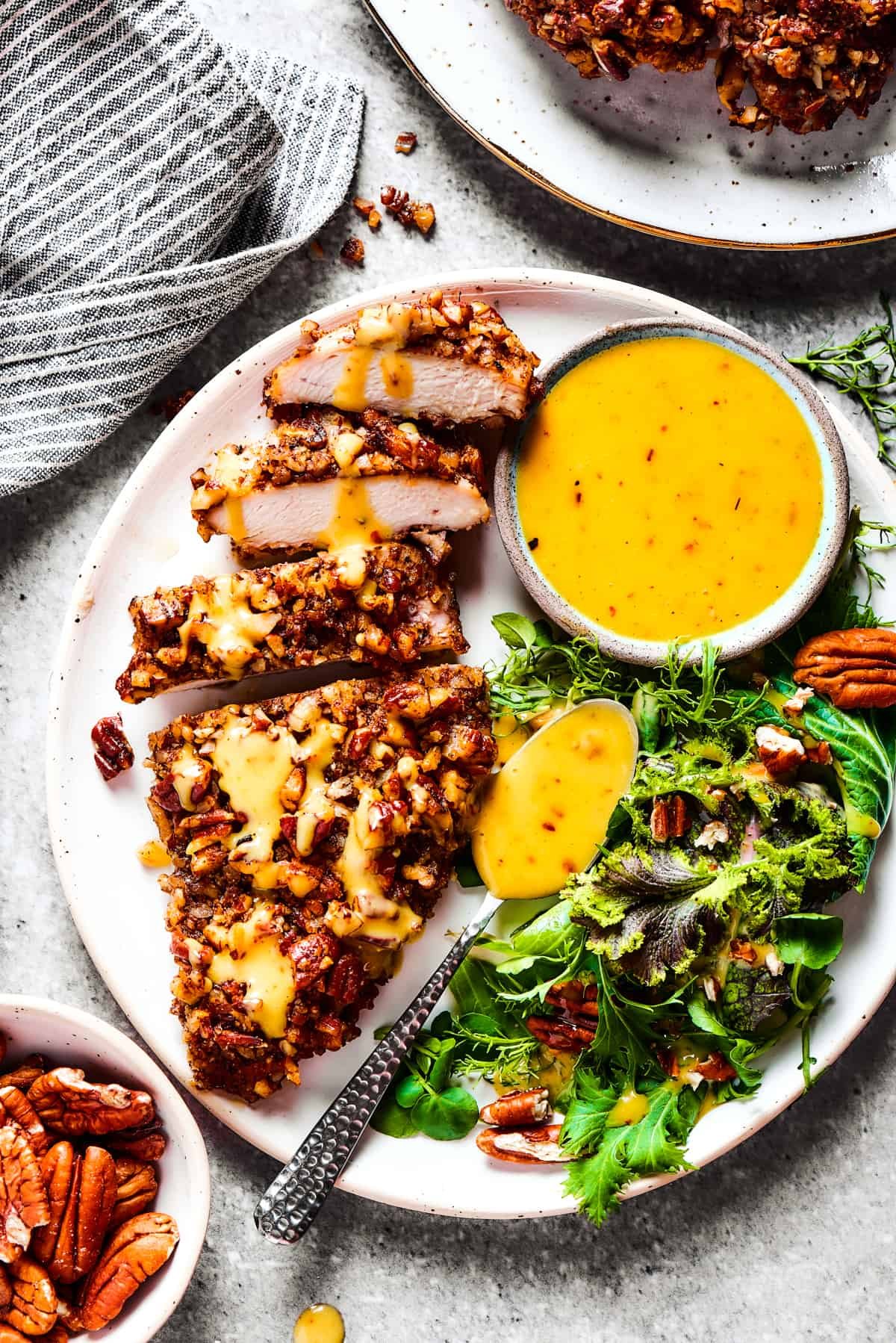 A breast of chicken cooked in pecan breading, sliced and served on a dinner plate.
