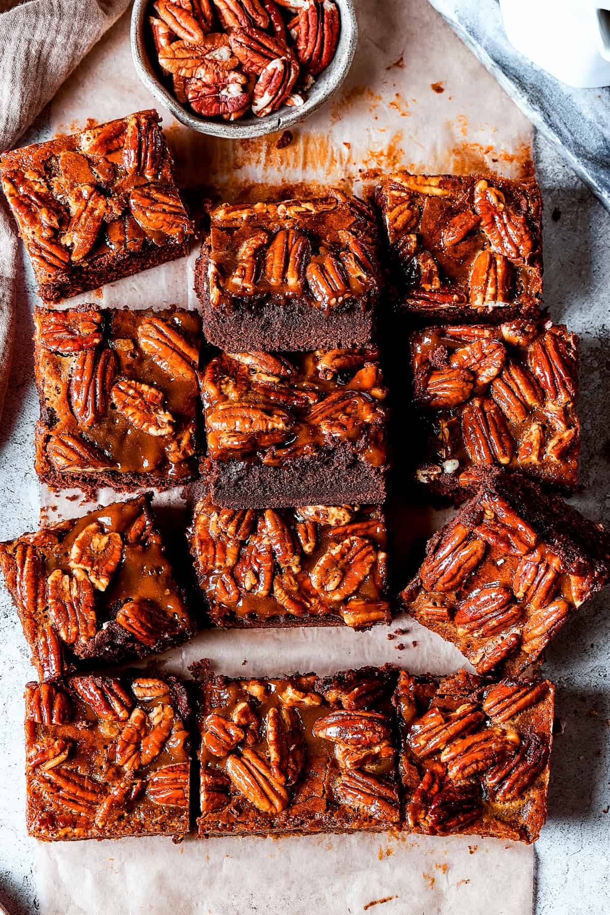 Pecan brownie squares arranged on a light surface.
